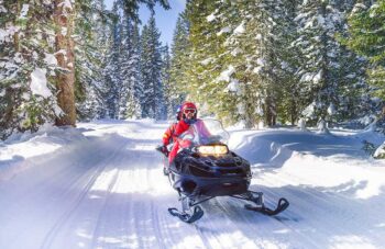 mother and son driving a snowmobile in  colorado, usa